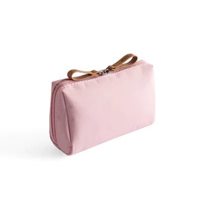 Pink toiletry bag with a brown strap on a white background