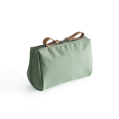 Green toiletry bag with a brown strap on a white background